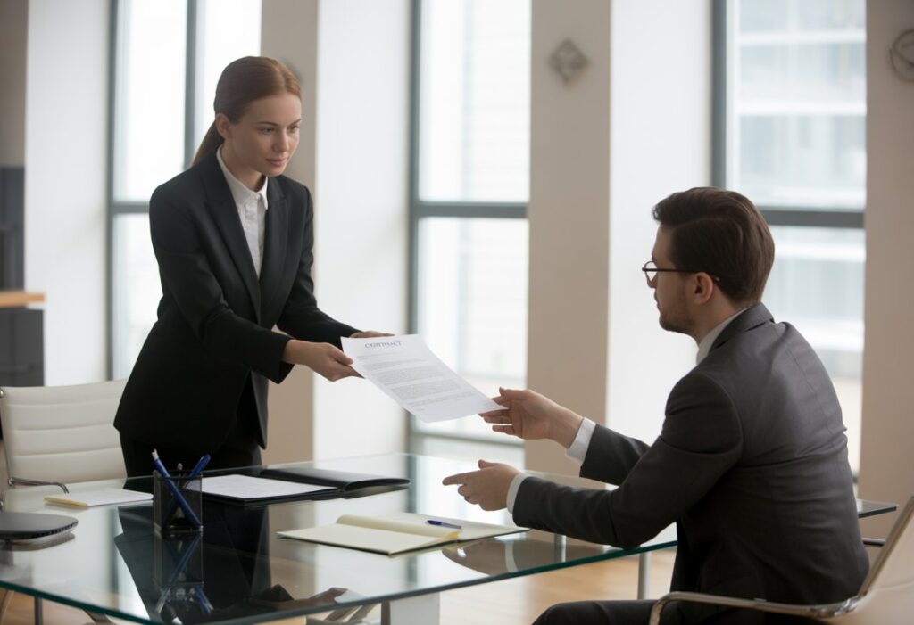 Twee mensen in een kantoor die een serieus gesprek voeren over een document op tafel.