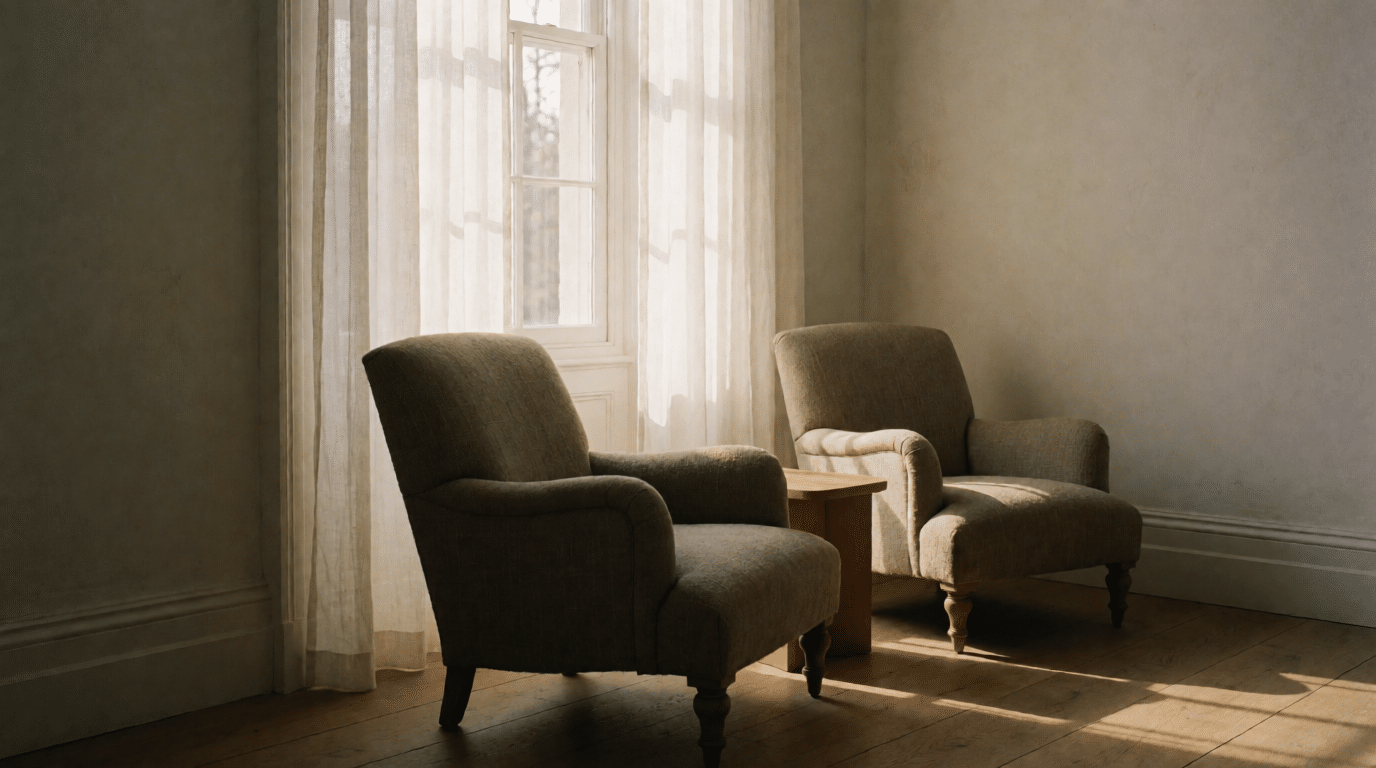 Twee lege fauteuils bij een raam met vitrage