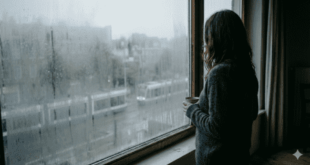 Vrouw bij raam die intieme terreur en dwingende controle binnen een relatie symboliseert tijdens een echtscheiding