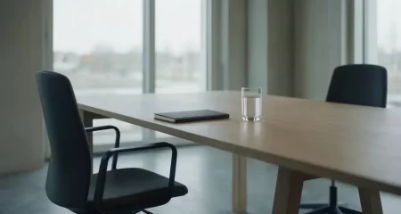 Lege vergaderruimte met twee bureaustoelen tegenover elkaar aan een lange houten tafel