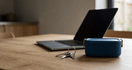 Keukentafel met een laptop, een broodtrommel en een sleutelbos