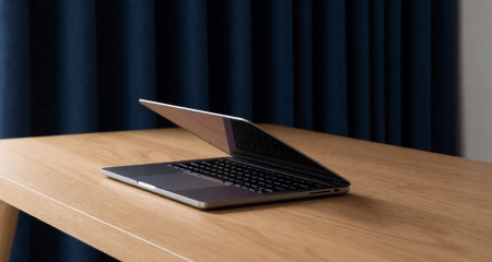 Halfgesloten laptop op een bureau in een kamer met dichte gordijnen