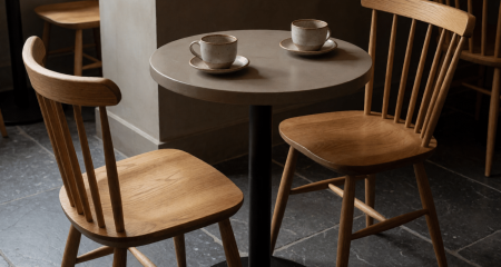 Twee lege stoelen aan een cafétafel met twee gebruikte koffiekopjes