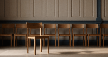Eén stoel iets apart van een rij stoelen tegen een lambriseringswand