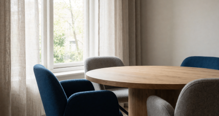 Rustige spreekkamer met een ronde tafel en zachte stoelen bij het raam