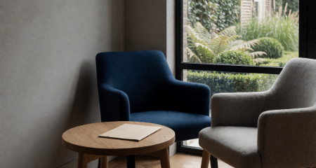 Twee fauteuils bij een tuinraam met een map op de bijzettafel