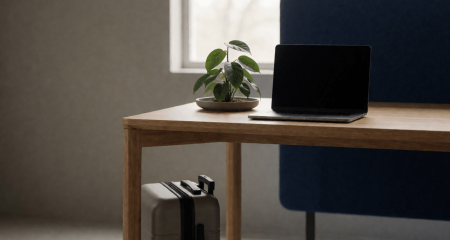 Modern bureau met een laptop, plant en een kleine koffer ernaast