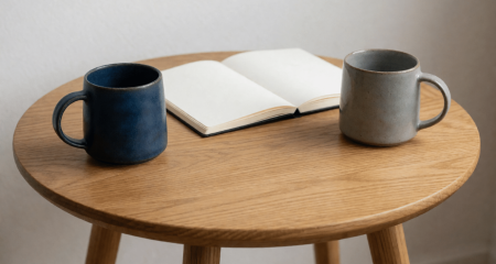 Twee mokken tegenover elkaar op een ronde tafel met een notitieboek ertussen