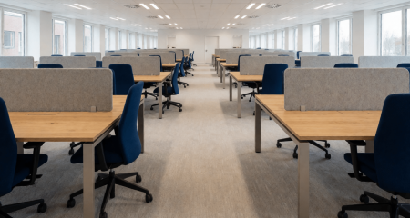 Grote kantoortuin met veel lege bureaus gezien door één gangpad