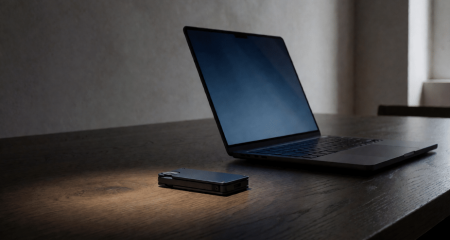 Hardware wallet en een laptop op een bureau in een schemerige ruimte
