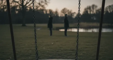 Leeg kinderschommel in een Nederlands park bij schemering, met twee volwassen silhouetten op afstand van elkaar — symbool voor een vechtscheiding en de kwetsbare positie van het kind.