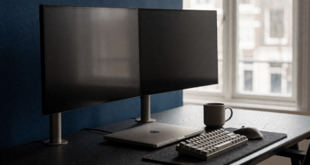 Werkplek met twee lege beeldschermen en een dichtgeklapte laptop