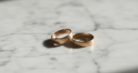 Twee trouwringen die uit elkaar liggen op een marmeren ondergrond, symbool voor een moeizame scheiding waarbij vermogensverdeling en manipulatief gedrag een rol spelen.