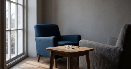 Woonkamer met twee fauteuils bij het raam en een leesbril op een bijzettafel