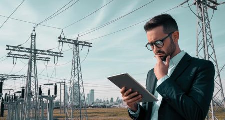 Man met tablet bij elektriciteitsmasten.