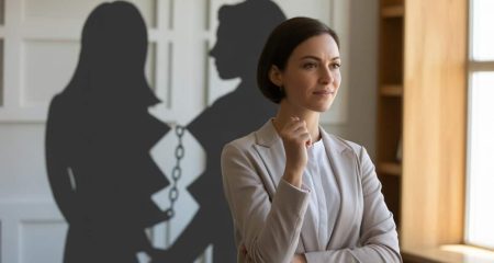 Een vrouw staat kalm en zelfverzekerd in een lichte kamer, met een gebroken ketting op de achtergrond die vrijheid symboliseert.