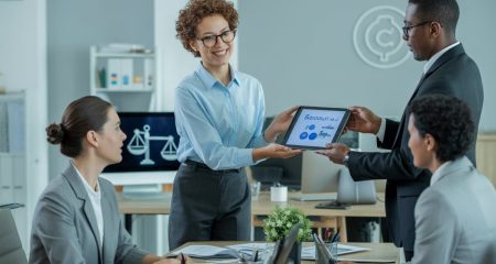 Een werknemer die een digitaal apparaat aan een manager overhandigt in een moderne kantooromgeving.