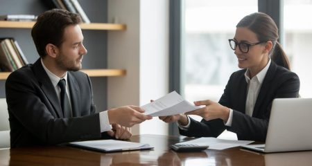 Twee zakelijke personen zitten aan een tafel en bespreken financiële documenten in een kantoor.