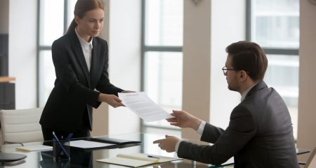 Twee mensen in een kantoor die een serieus gesprek voeren over een document op tafel.