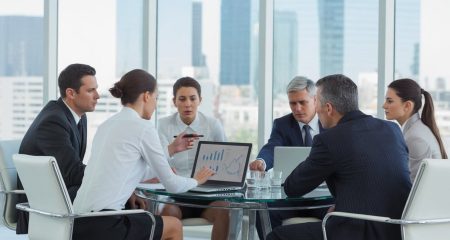 Een groep zakelijke professionals bespreekt een probleem rond een vergadertafel in een modern kantoor.
