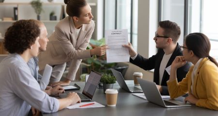 Een groep freelancers en zzp’ers in een kantoorruimte bespreekt een contract aan een tafel.