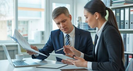 Twee zakelijke professionals bespreken een contract in een kantooromgeving.