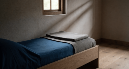 Kleine kale kamer met een smal bed en een hoog raam