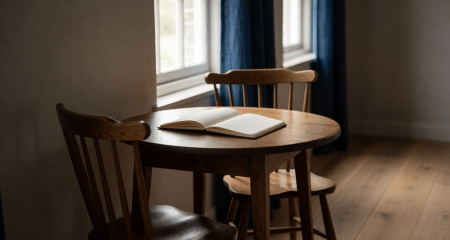 Twee dicht bij elkaar geschoven stoelen aan een tafel met een open notitieboek