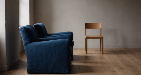 Twee fauteuils en een derde stoel iets apart in een neutrale ruimte