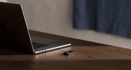 Laptop op een donker bureau met een kleine hardwaresleutel ernaast