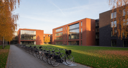 Universiteitscampus met bakstenen gebouwen, geparkeerde fietsen en een grasveld